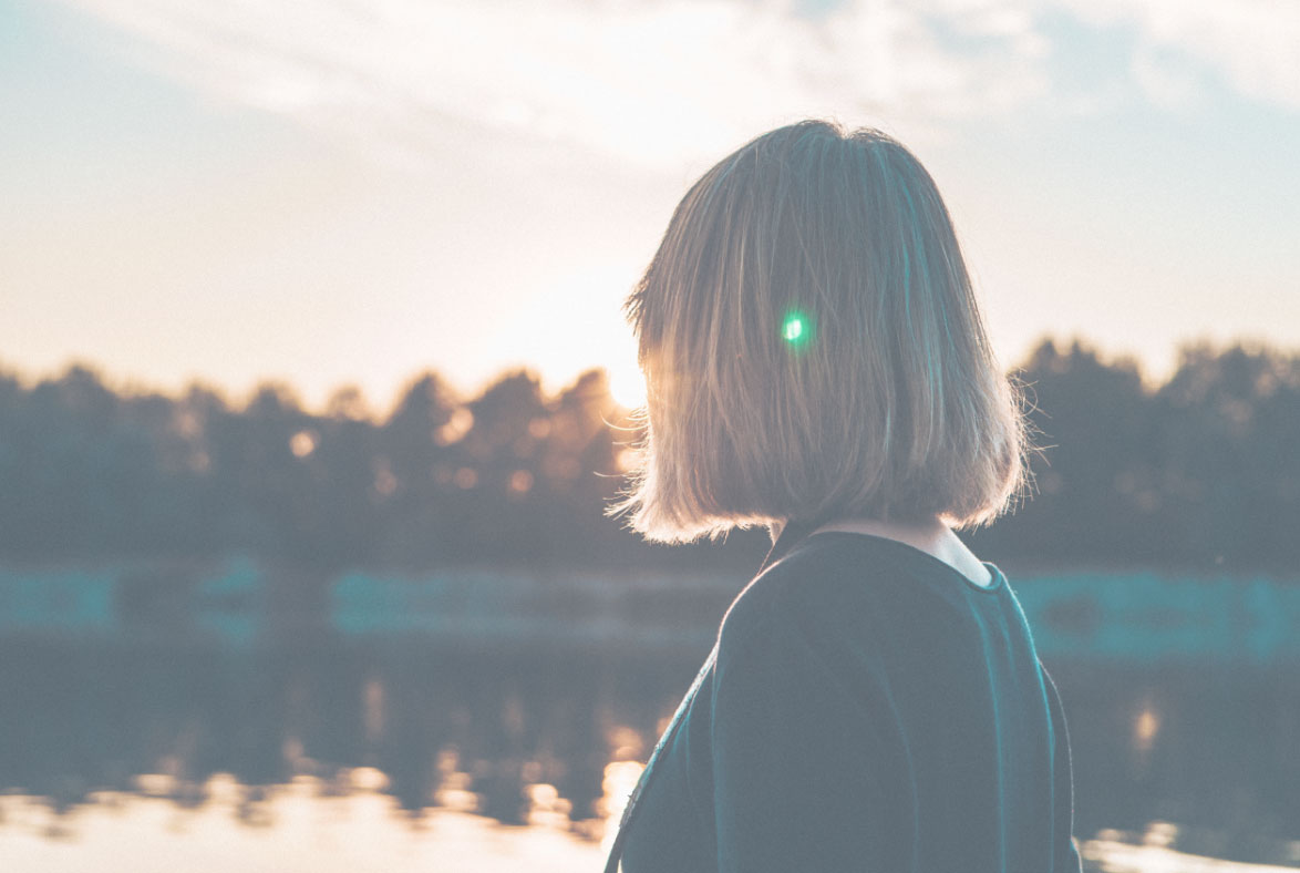 Frau blickt auf See und Sonnenuntergang – Mood Foto Entspannung und Regeneration